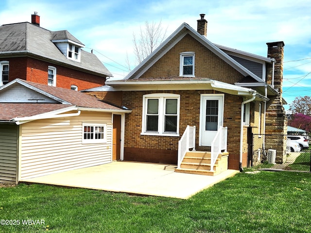 rear view of house featuring a patio area, fence, brick siding, a yard, and a chimney