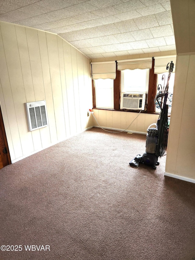 spare room with cooling unit, wood walls, heating unit, and carpet floors