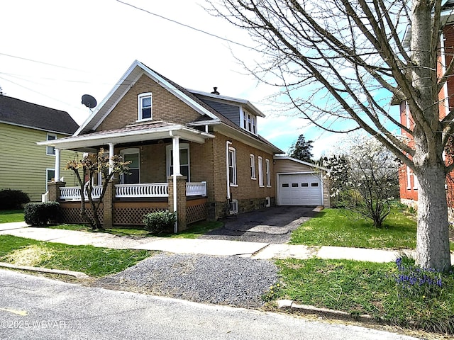 view of front of property featuring driveway, an outbuilding, brick siding, covered porch, and a garage