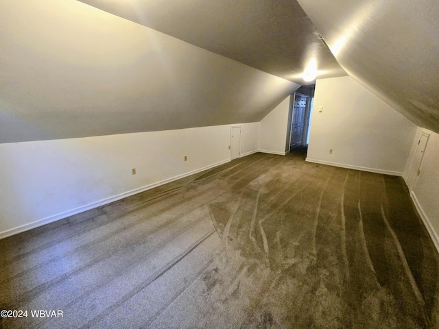 bonus room with dark carpet and vaulted ceiling