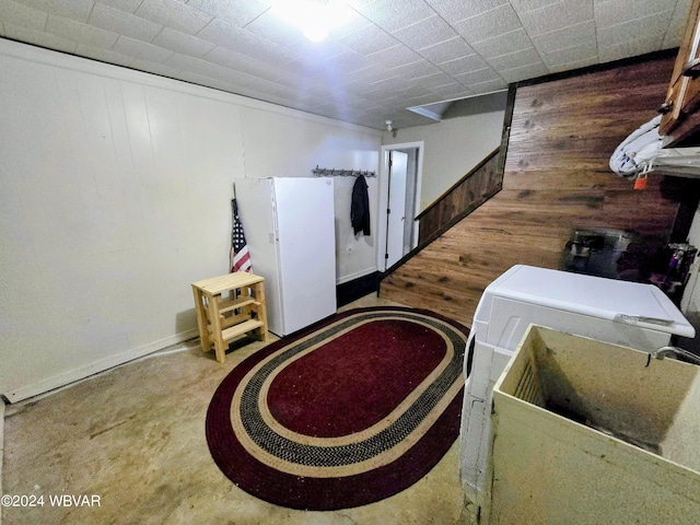 interior space with white fridge, wooden walls, and sink