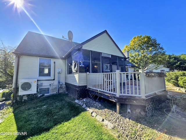 rear view of property featuring a yard, a sunroom, ac unit, and a deck