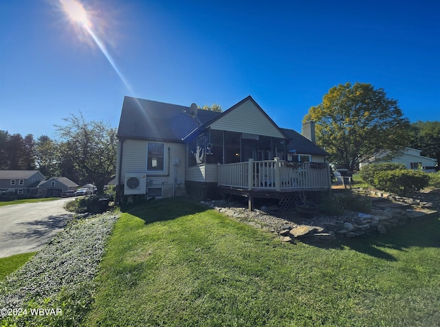 rear view of property with a lawn, ac unit, a deck, and a sunroom