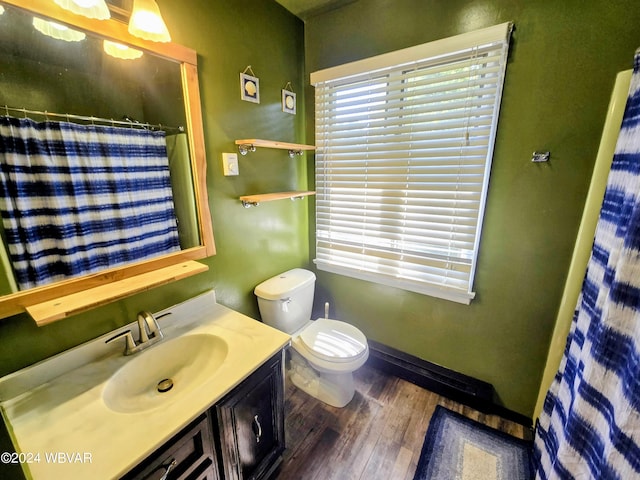 bathroom with a shower with shower curtain, hardwood / wood-style floors, vanity, and toilet