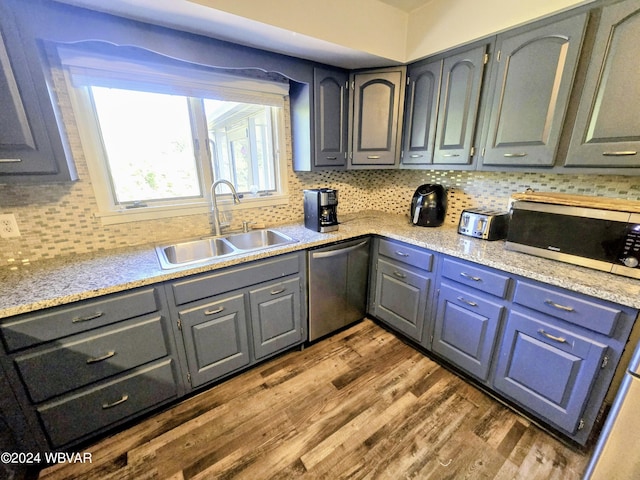 kitchen featuring appliances with stainless steel finishes, backsplash, light stone counters, sink, and dark hardwood / wood-style floors