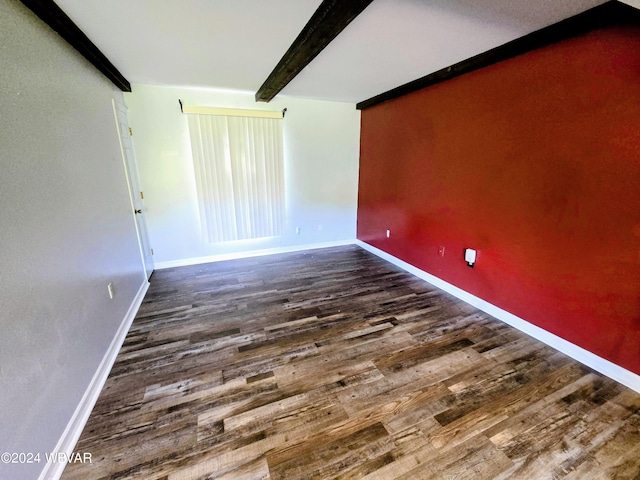 empty room featuring beamed ceiling and dark hardwood / wood-style floors