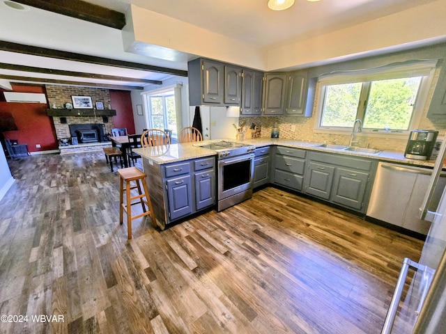 kitchen with kitchen peninsula, sink, a healthy amount of sunlight, and appliances with stainless steel finishes