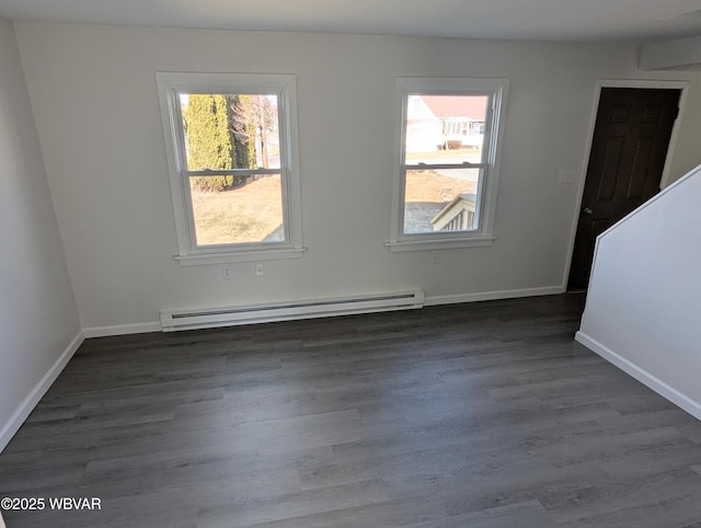 unfurnished room with a baseboard heating unit and dark hardwood / wood-style floors