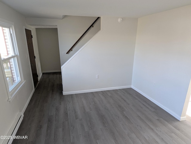 unfurnished room with a baseboard heating unit and dark hardwood / wood-style flooring