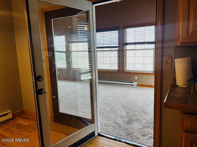 doorway to outside featuring a baseboard heating unit and light wood-type flooring