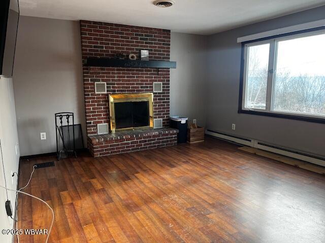 unfurnished living room featuring hardwood / wood-style floors, a brick fireplace, and a baseboard heating unit