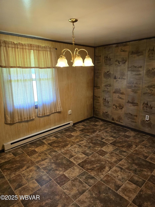 spare room with a baseboard heating unit, wood walls, and an inviting chandelier