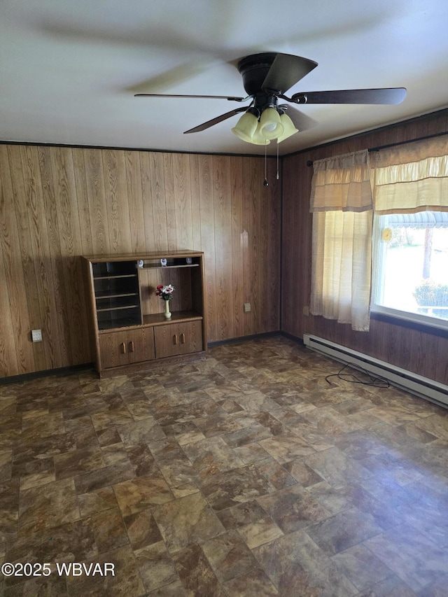 unfurnished living room with a baseboard heating unit, wood walls, and ceiling fan