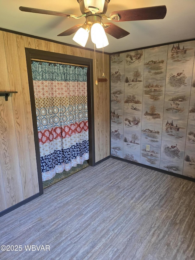 unfurnished room with wood walls, baseboards, wood finished floors, and ceiling fan