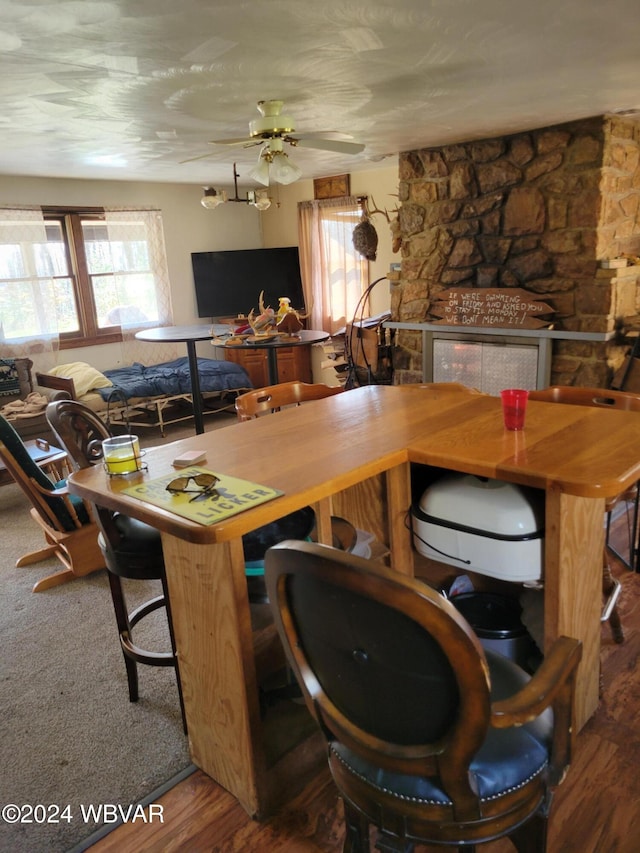 dining room featuring ceiling fan, a fireplace, and wood-type flooring