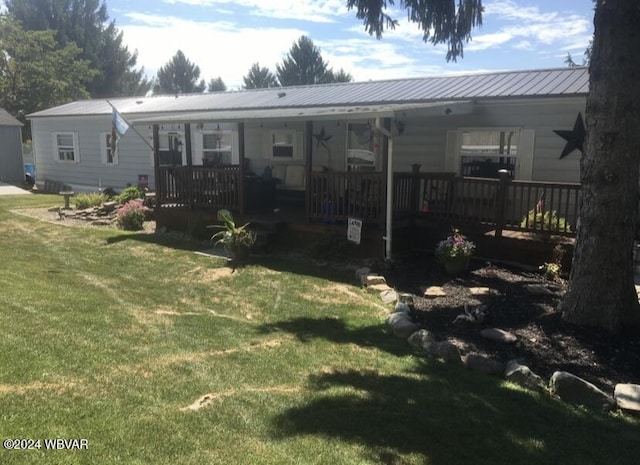 rear view of property with metal roof, a lawn, and covered porch