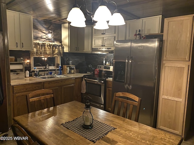 kitchen featuring light countertops, hanging light fixtures, stainless steel appliances, a sink, and decorative backsplash