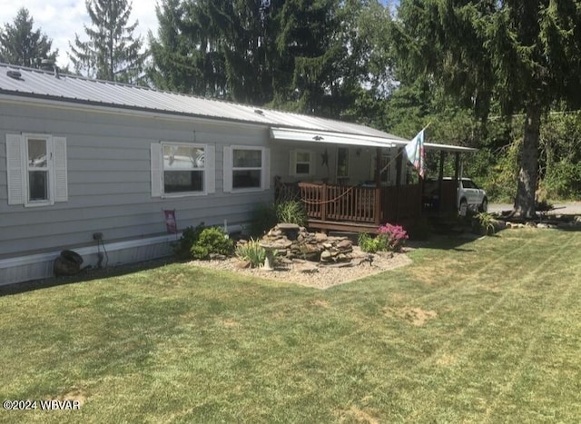 back of house with metal roof and a yard