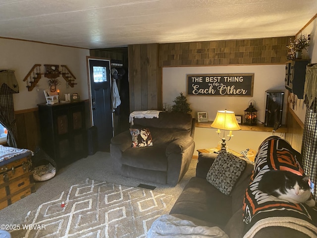 carpeted living room with ornamental molding and wood walls