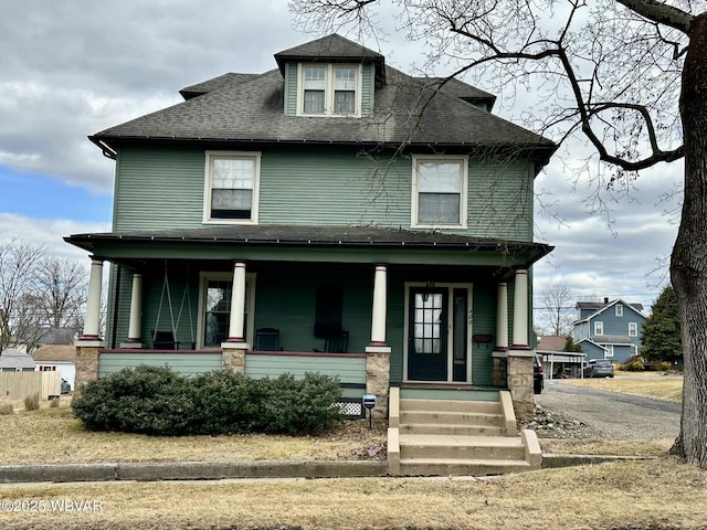 american foursquare style home featuring covered porch and a shingled roof