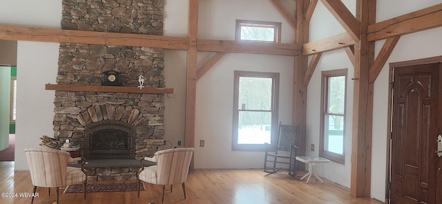 living room featuring a towering ceiling, light hardwood / wood-style floors, and a stone fireplace