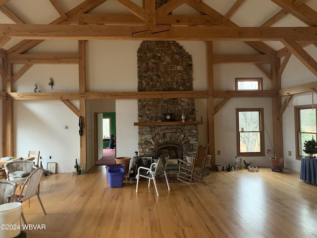 living room featuring a stone fireplace, high vaulted ceiling, and light hardwood / wood-style flooring