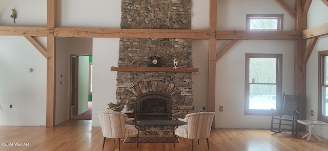 living room featuring a stone fireplace, plenty of natural light, and a towering ceiling