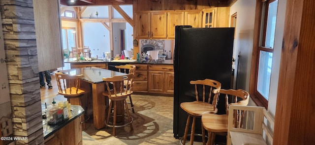 kitchen with a breakfast bar, a center island, and black refrigerator