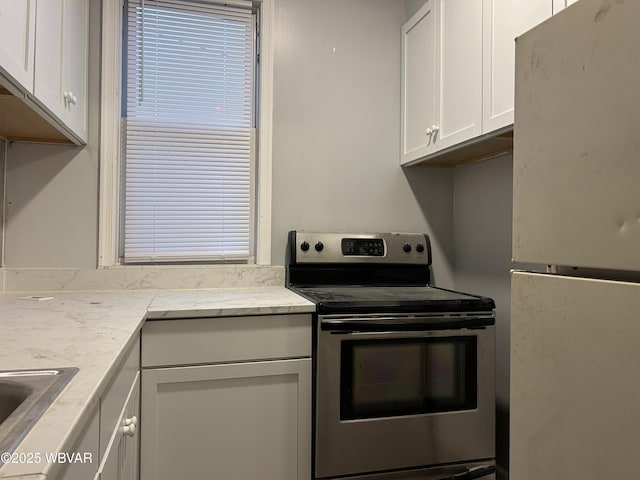 kitchen featuring white cabinetry, sink, refrigerator, and stainless steel electric range oven