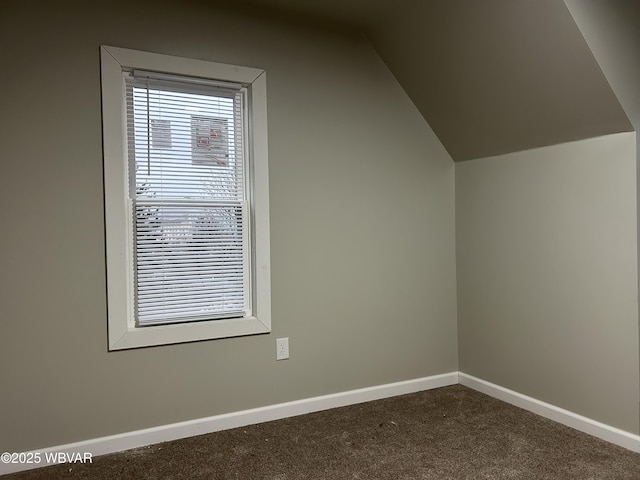 bonus room with dark carpet and vaulted ceiling