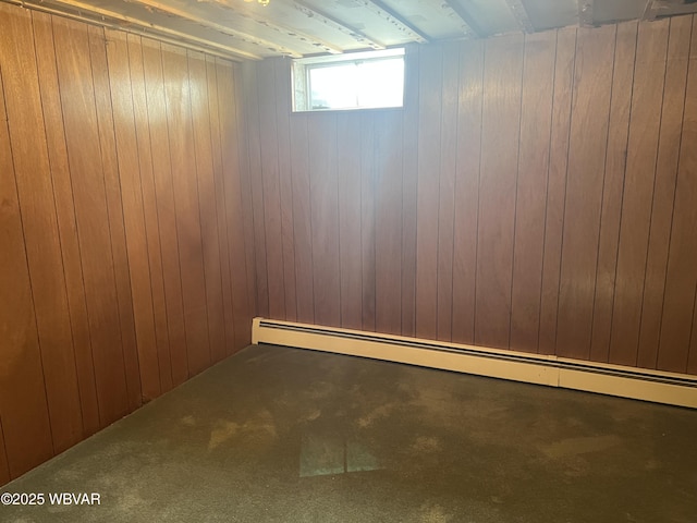 below grade area with a baseboard heating unit, wood walls, and carpet flooring