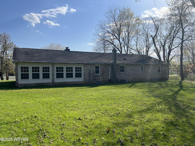 back of property with brick siding, a yard, and crawl space