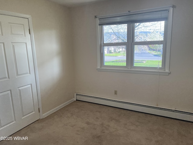 unfurnished room featuring baseboards, baseboard heating, and light colored carpet