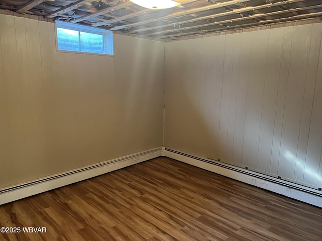 basement with a baseboard heating unit, wood finished floors, and wooden walls