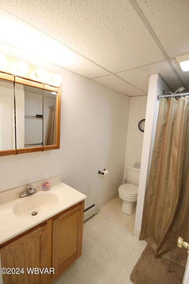 bathroom featuring a drop ceiling, vanity, toilet, baseboard heating, and walk in shower