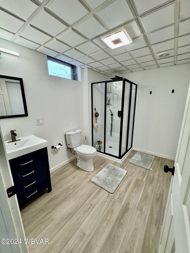 bathroom with hardwood / wood-style floors, vanity, a paneled ceiling, toilet, and a shower with shower door