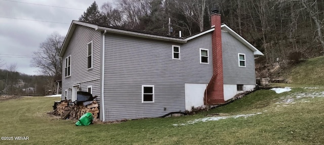 view of side of home featuring a lawn and a chimney