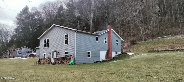 view of side of property with a yard and a chimney