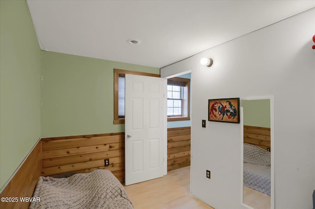 bedroom featuring wood walls and light hardwood / wood-style flooring