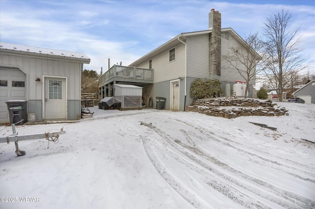 snow covered property with a garage and a deck