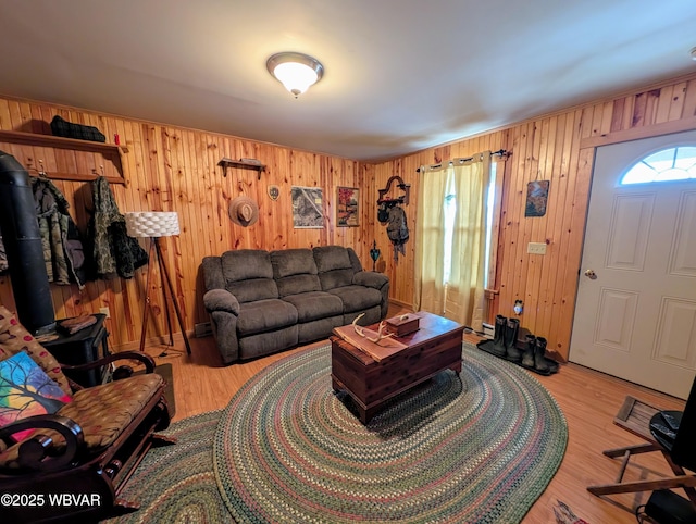 living room featuring wood walls, light hardwood / wood-style floors, and a wood stove