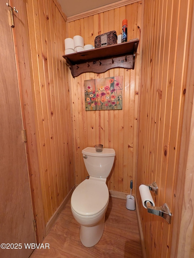 bathroom featuring wooden walls, wood-type flooring, and toilet