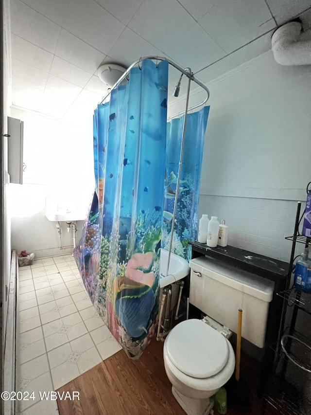 bathroom with wood-type flooring, toilet, and shower / bath combo with shower curtain