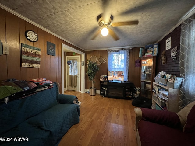 living room with hardwood / wood-style flooring, ceiling fan, crown molding, and wooden walls