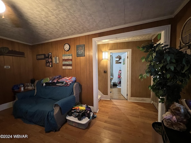 living area with ornamental molding, light hardwood / wood-style flooring, and wooden walls