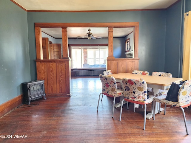 dining room featuring hardwood / wood-style floors, a wood stove, radiator, ceiling fan, and ornamental molding