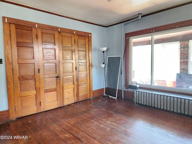 unfurnished bedroom with dark hardwood / wood-style floors, radiator heating unit, and crown molding