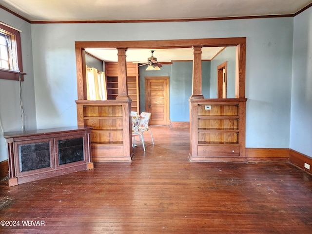 unfurnished living room with dark hardwood / wood-style floors, ceiling fan, crown molding, and decorative columns