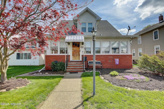 104 Pearl St, Lock Haven, PA 17745 - view of front facade featuring entry steps, brick siding, a front lawn, and roof with shingles