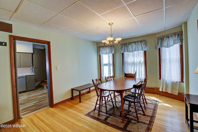 104 Pearl St, Lock Haven, PA 17745 - dining space featuring a paneled ceiling, a chandelier, light wood-style flooring, baseboard heating, and baseboards